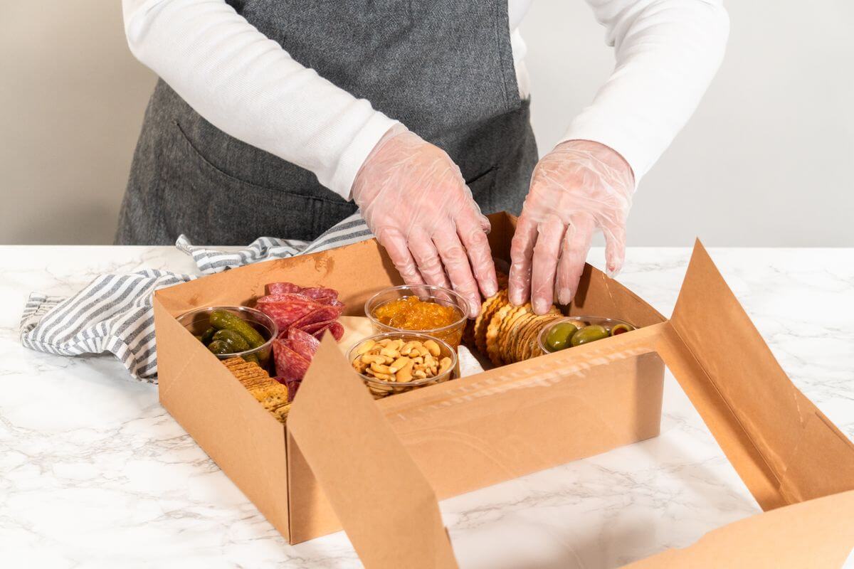 Traiteur entain de préparer une box de charcuterie à livrer