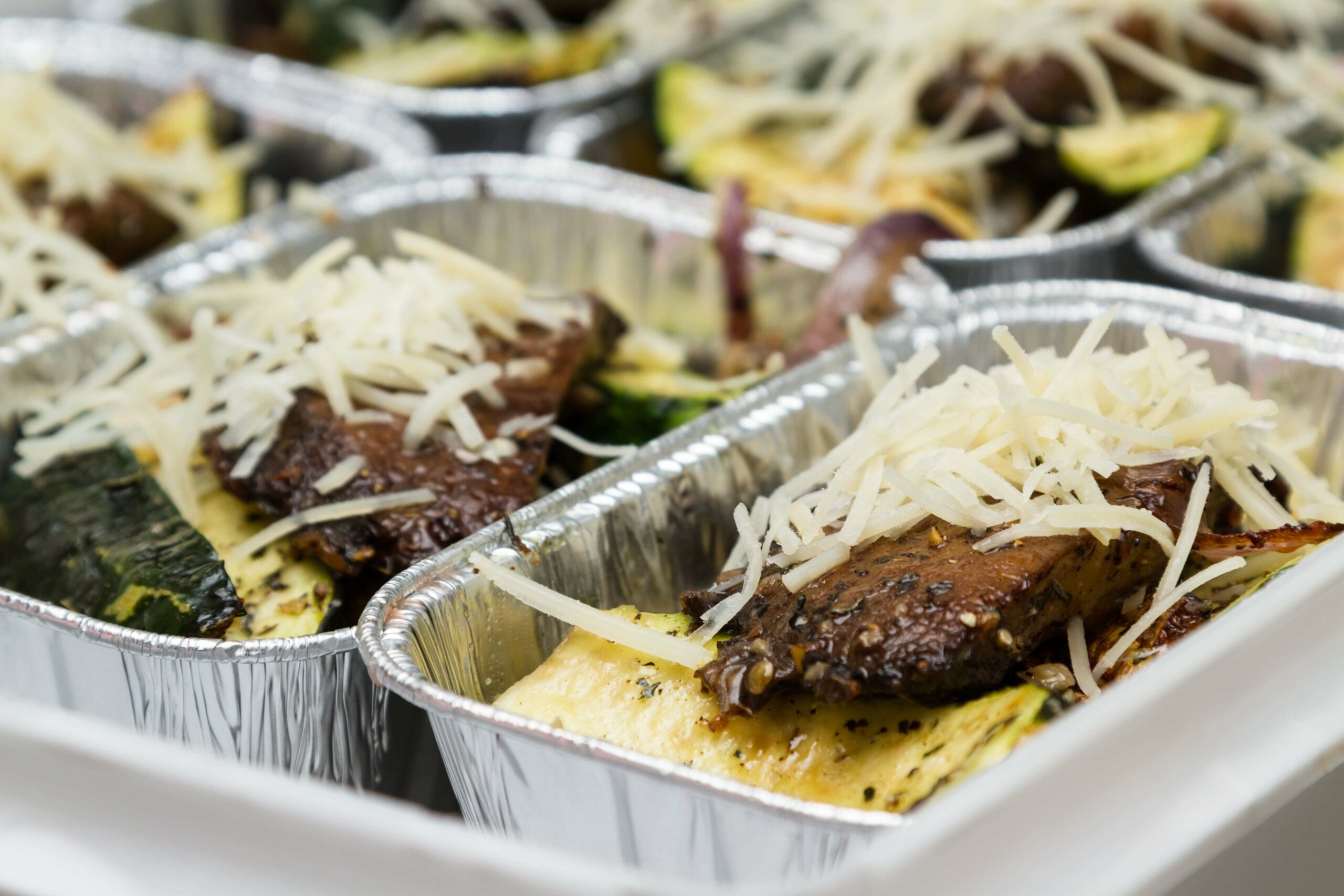 Plateau repas fait maison avec viande marinée aux herbes, courgettes grillées et parmesan frais râpé.